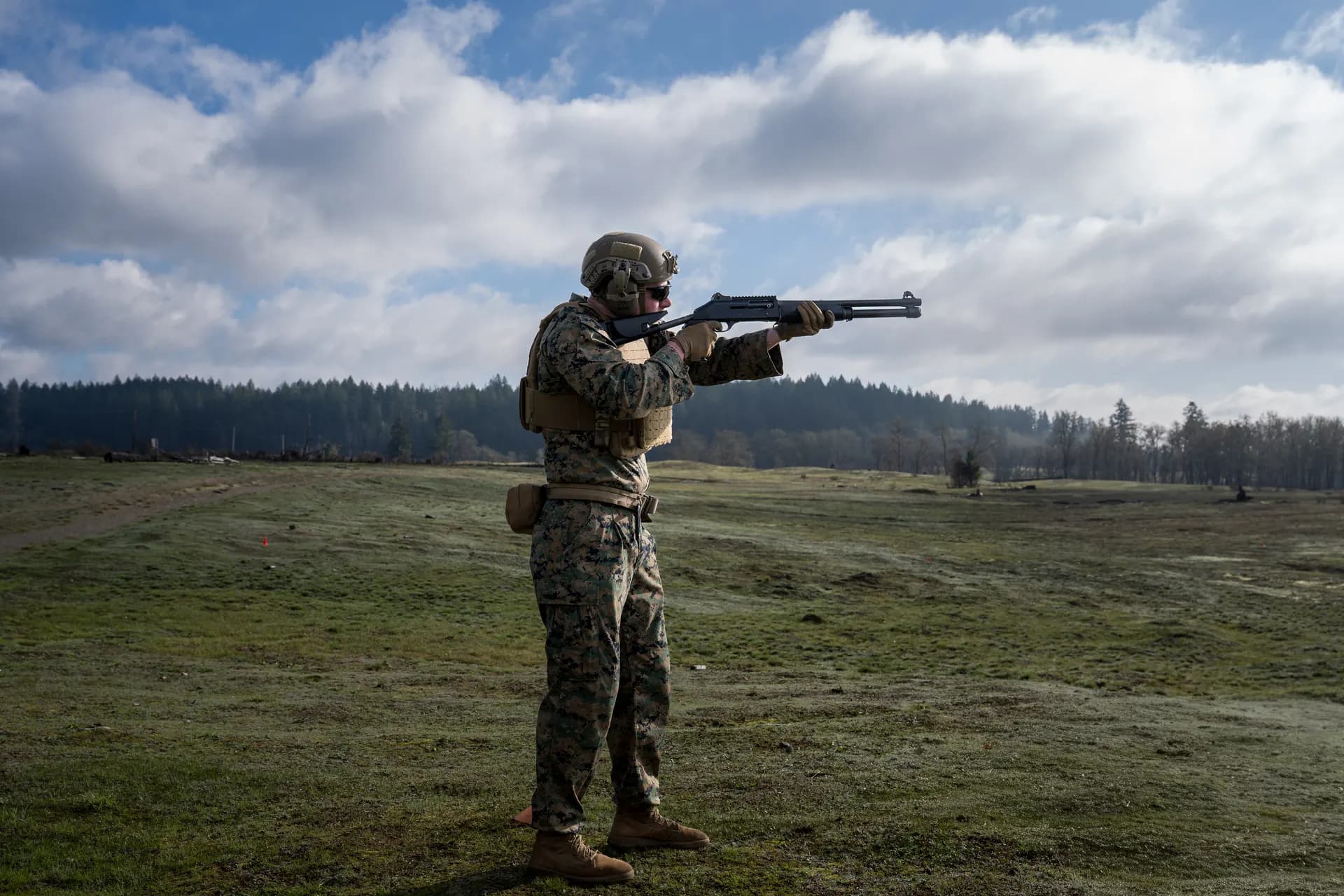 Marine aiming shotgun in full kit in open field