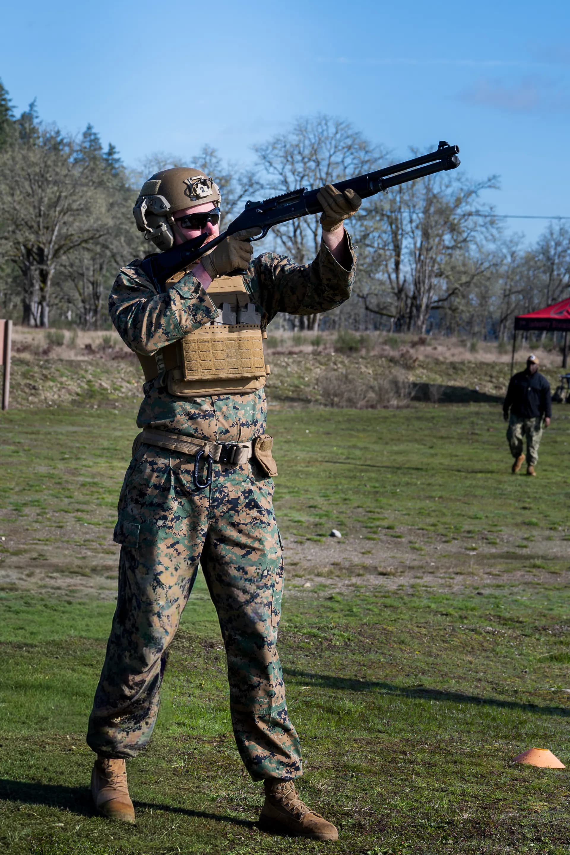 Marine in full kit aiming shotgun at range in sunny conditions