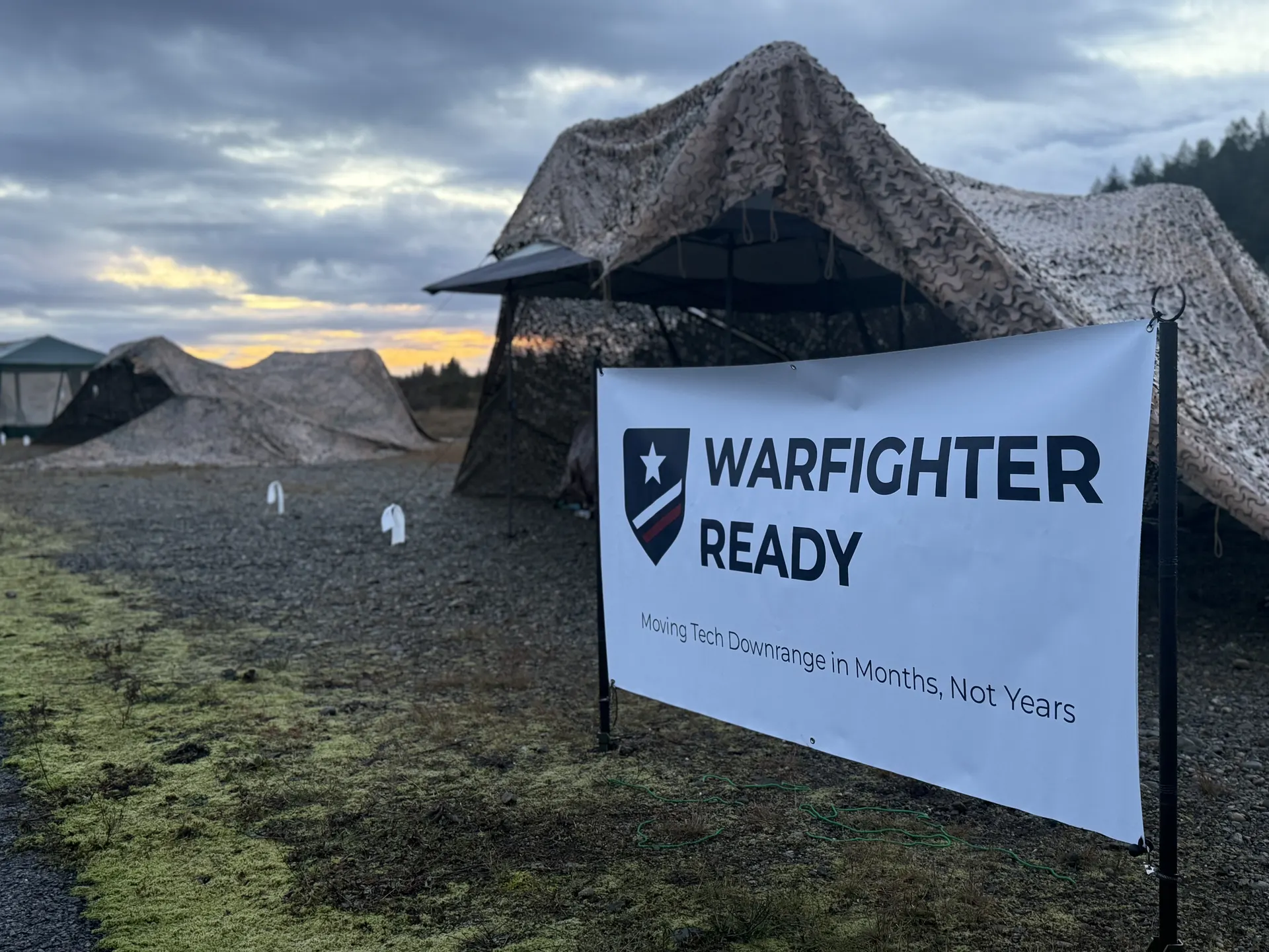 Warfighter Ready banner at dusk with dramatic sky over camo tents