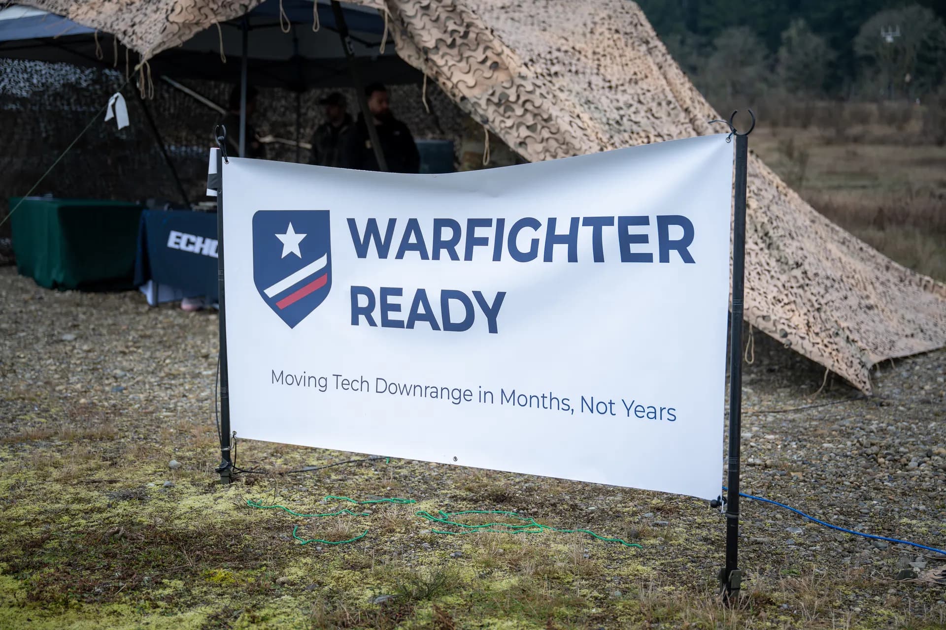 Warfighter Ready banner at field event with camo tent
